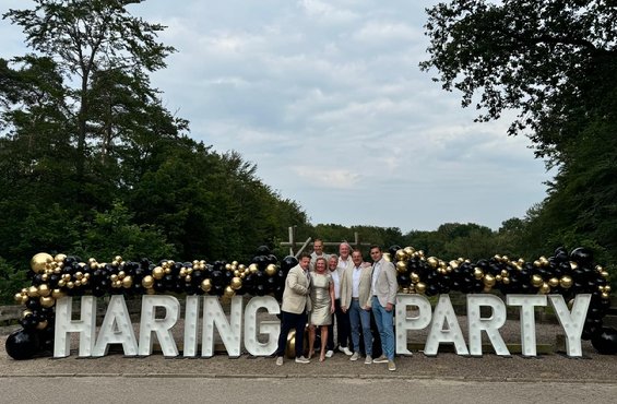 A group of people standing in front of a sign

Description automatically generated